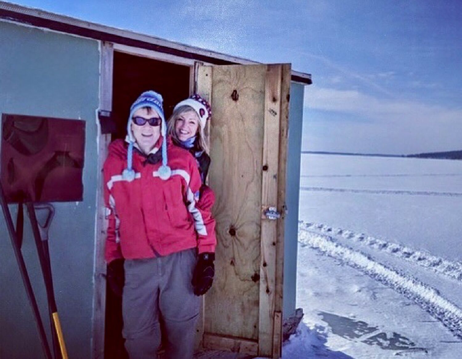 A small wooden structure with a door, likely a cabin or shelter, situated in a snowy landscape.