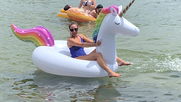 Une personne chevauche une licorne gonflable sur un plan d'eau.
