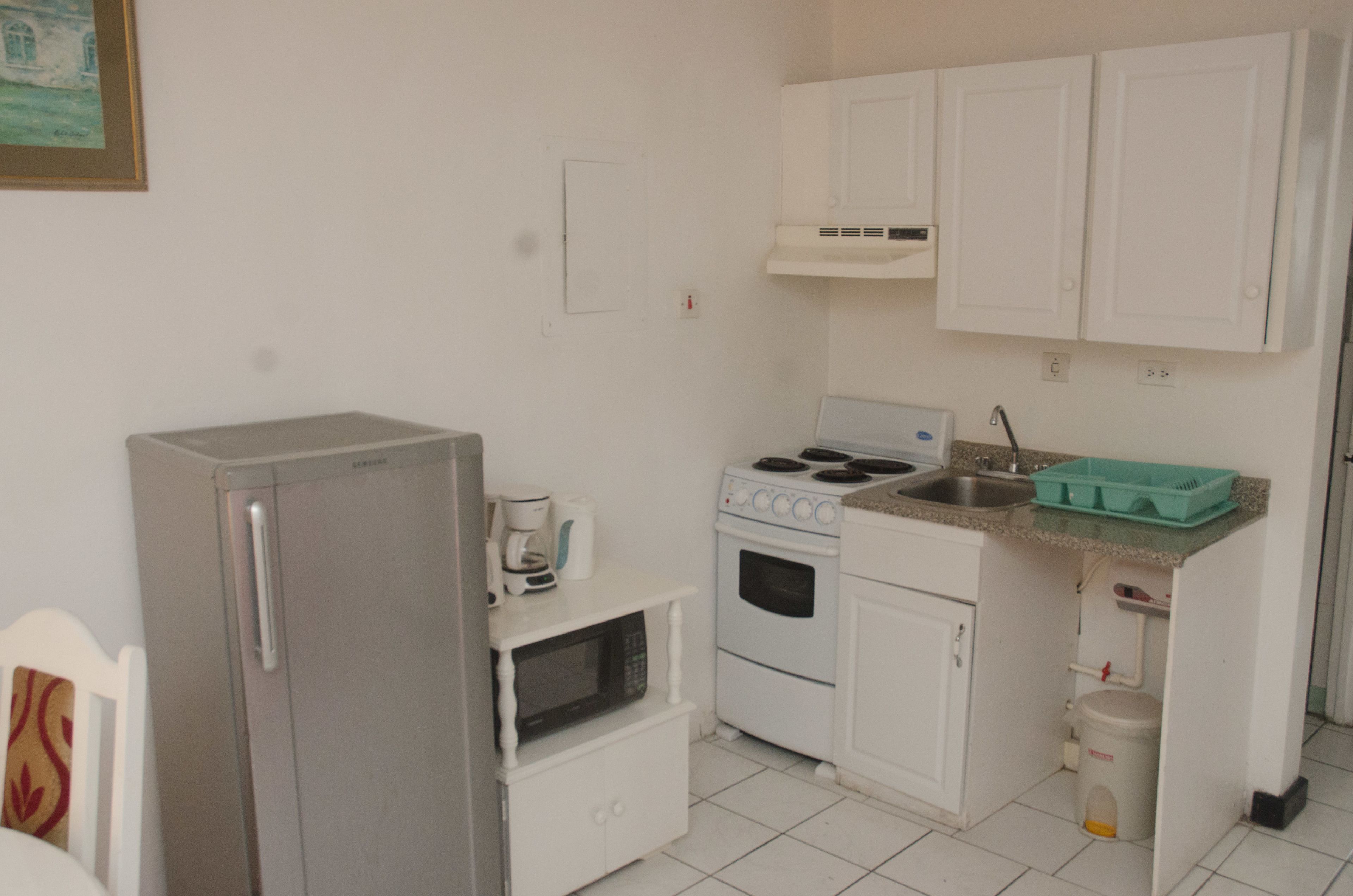 A compact kitchen with a refrigerator, microwave, stove, and sink.