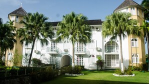 A large, multi-story building with a symmetrical facade, multiple balconies, and a central arched entrance. - Conch Shell Studio at Sandcastles (Ocho Rios)