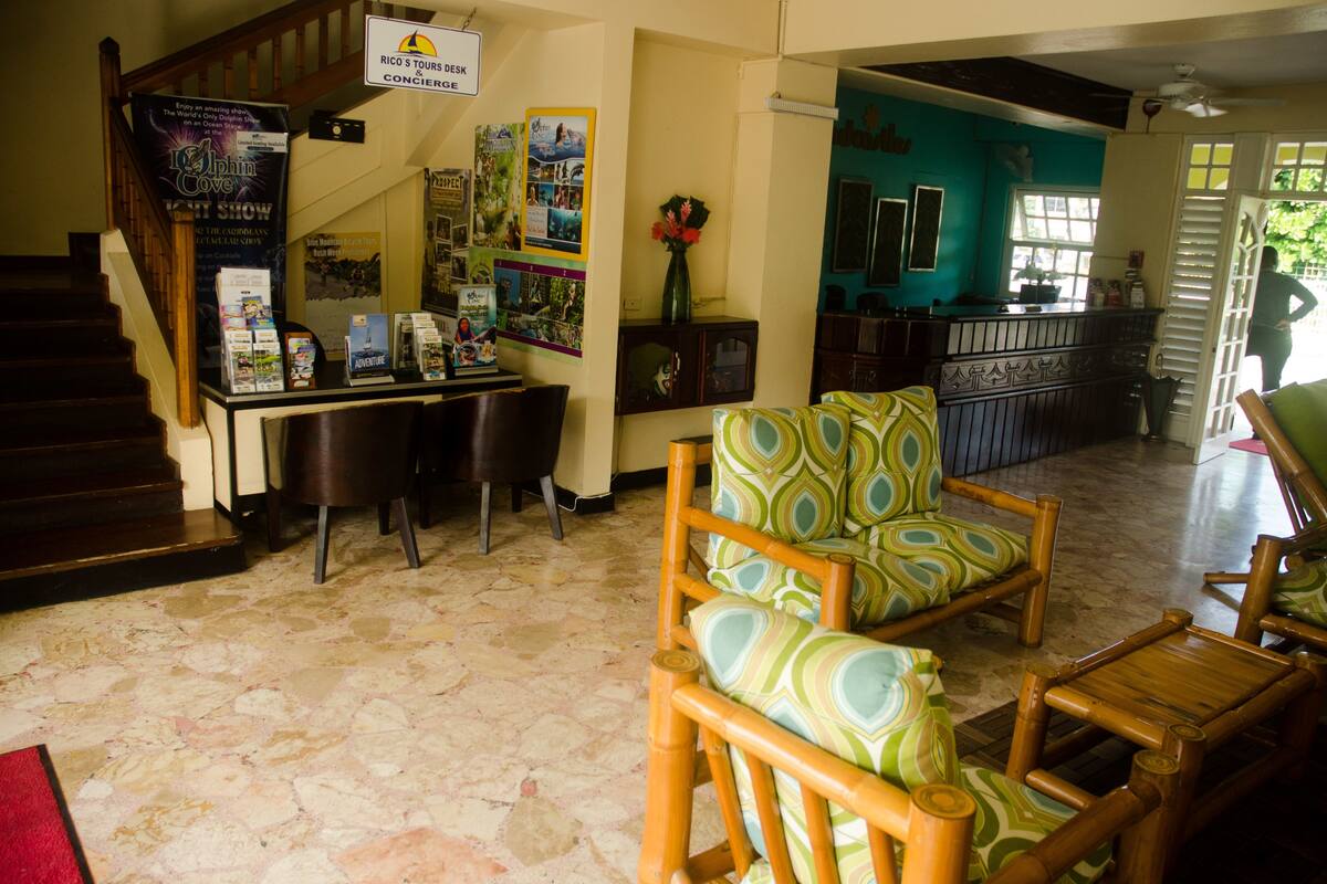 A lobby with a reception desk, a staircase, and a seating area with patterned chairs.