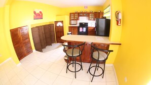 Una cocina con barra, armarios de madera y un refrigerador negro.