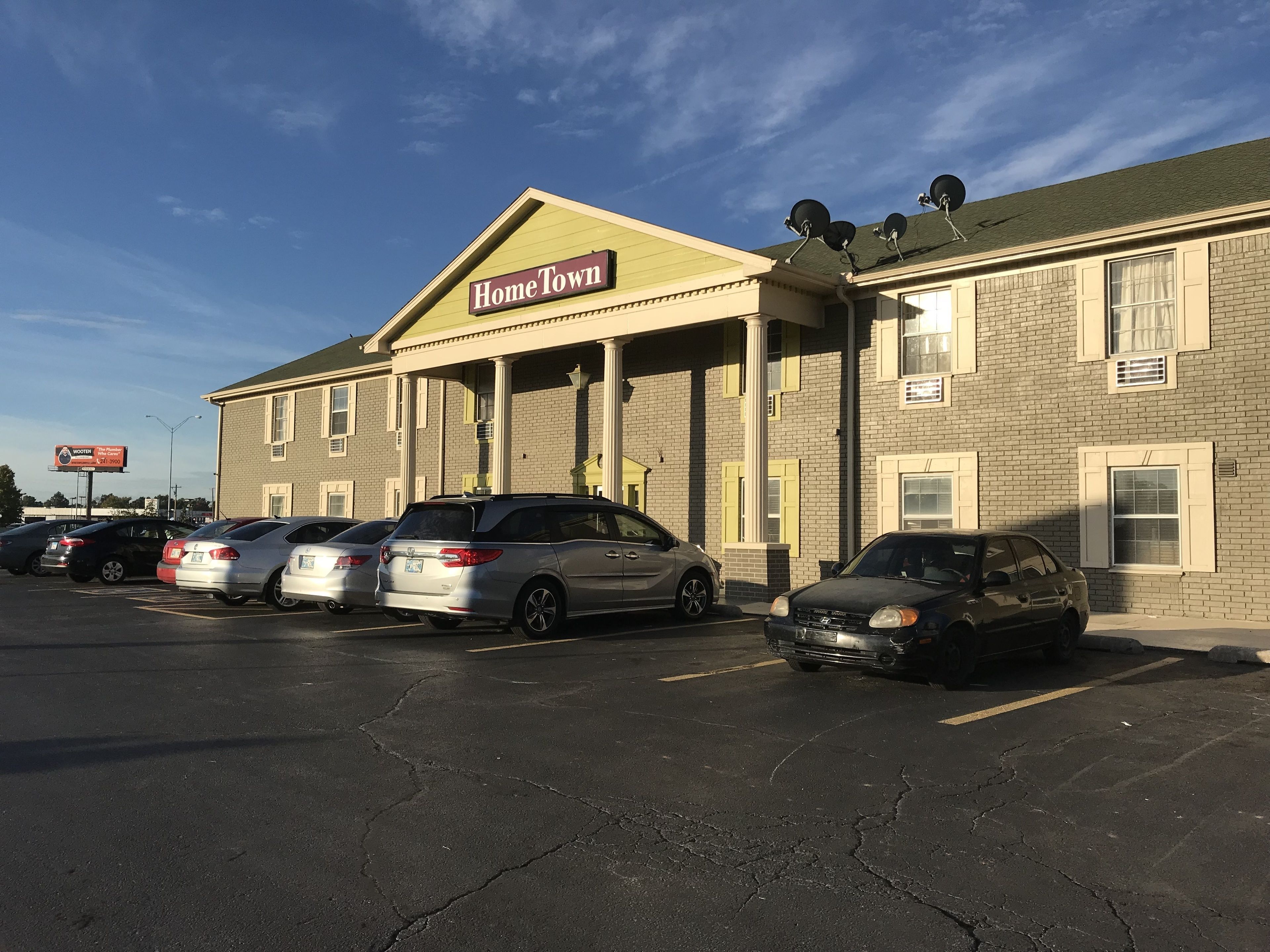 A building with a "HomeTown" sign, parking lot, and several parked cars.