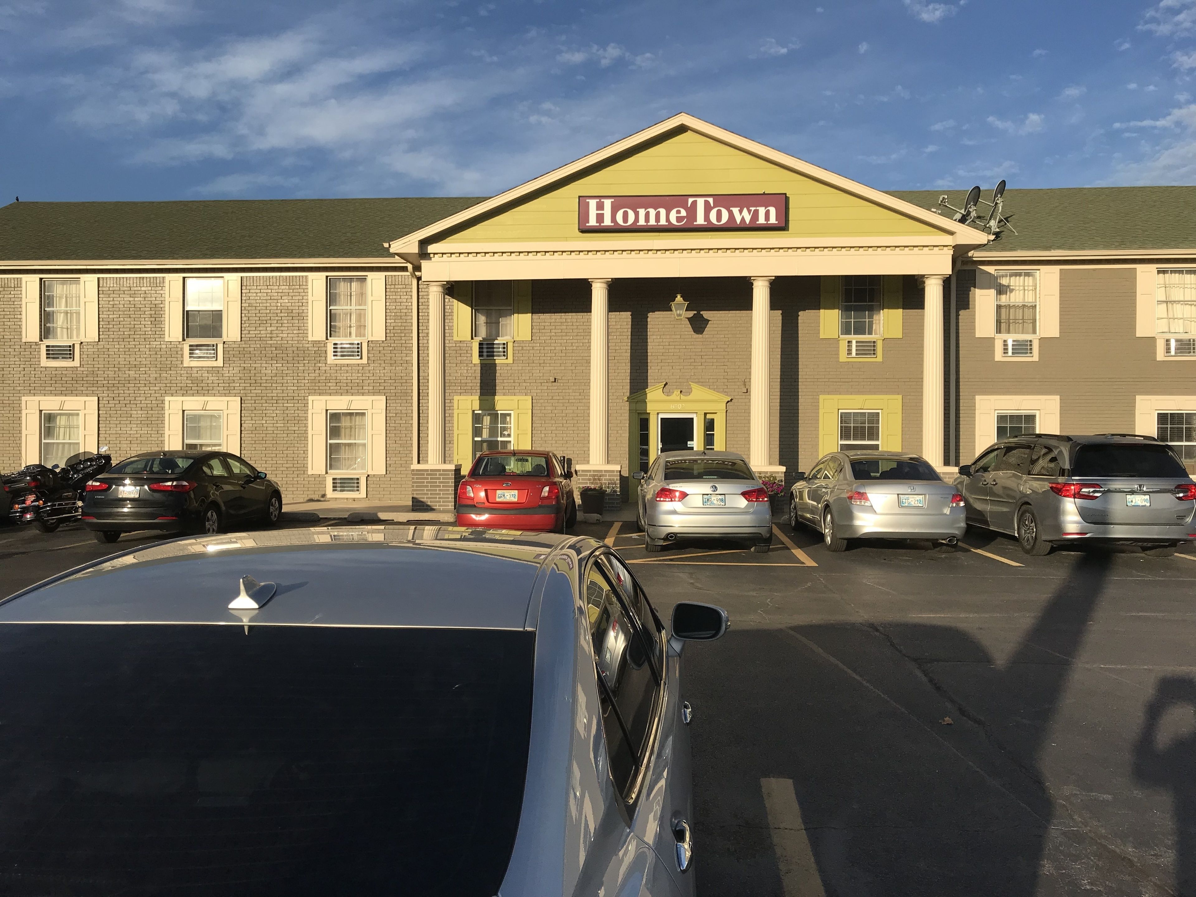 A building with a sign reading "HomeTown" and a parking lot with several cars.