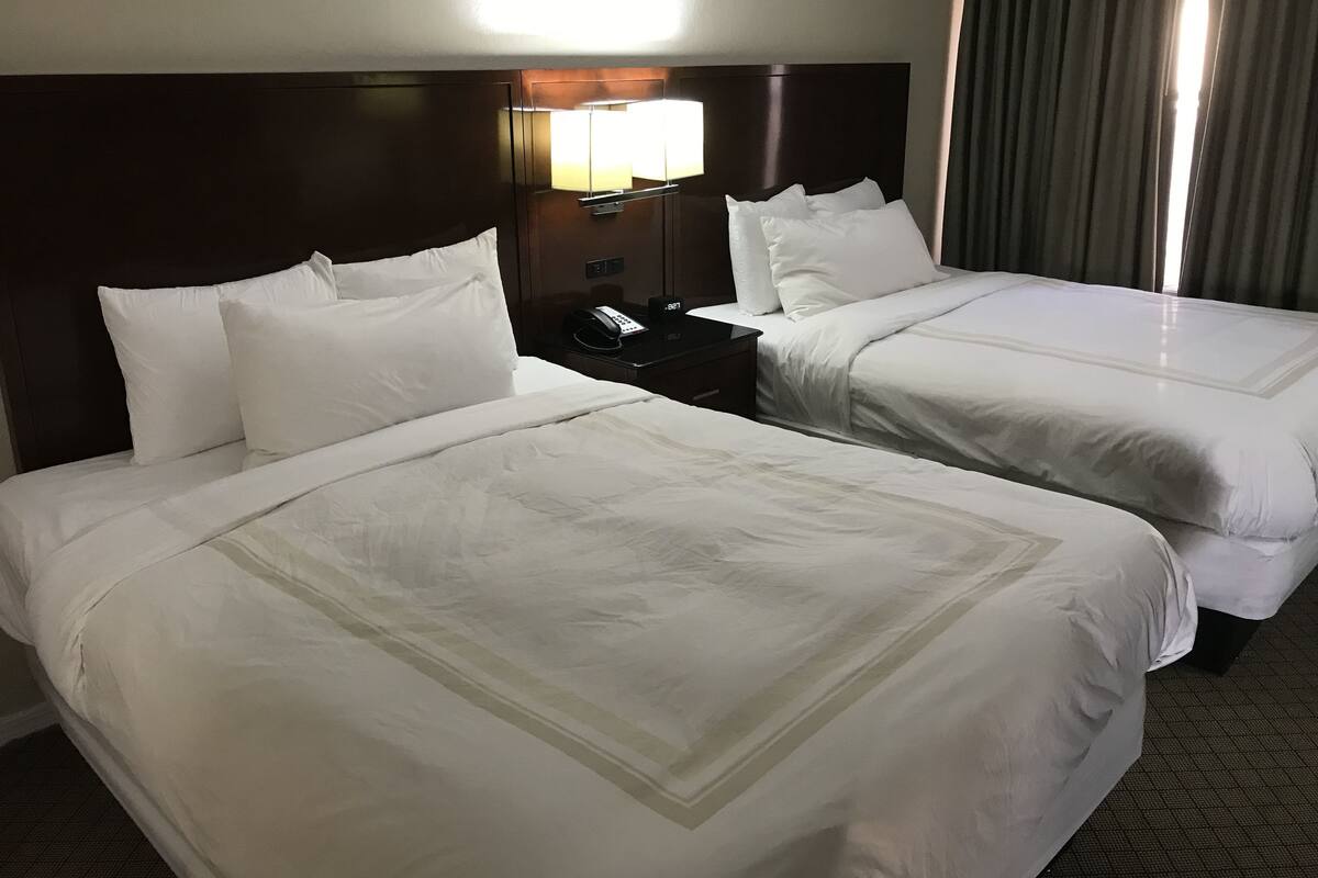 Une chambre d’hôtel avec deux lits, une table de chevet avec un téléphone et une lampe.