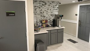 A storage area with a coffee machine, a trash bin, and a wall with a patterned design.