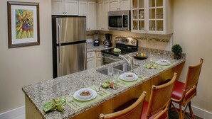A kitchen with granite countertops, stainless steel appliances, and a breakfast setup with plates and cutlery. - Turtle Cay - Key-West Style 2Bedrm 2.5bath Full Week Oceanview July 10-17 (Virginia Beach)