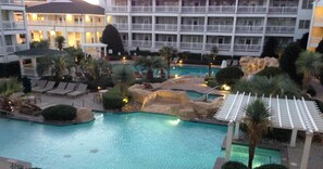 Un complex turístic amb piscina, gandules i un edifici amb nombroses balconades.