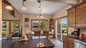 A spacious kitchen with a large island, wooden cabinets, and a view of a mountain landscape. - Tranquil Home Along the Yellowstone River (Emigrant)