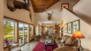 A spacious living room with a fireplace, a dining area, and a kitchen. - Tranquil Home Along the Yellowstone River (Emigrant)