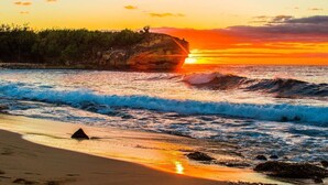 A beach with waves, a rock formation, and a sunset. - 3BR/3BA Villa: Central A/C! Short Walk To Beach! (Koloa)