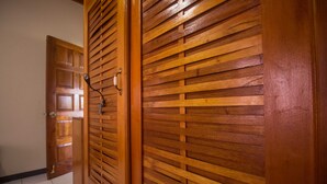 A hallway with wooden paneling and a door with a handle and a lock. - Rainbow Hill (Negril)