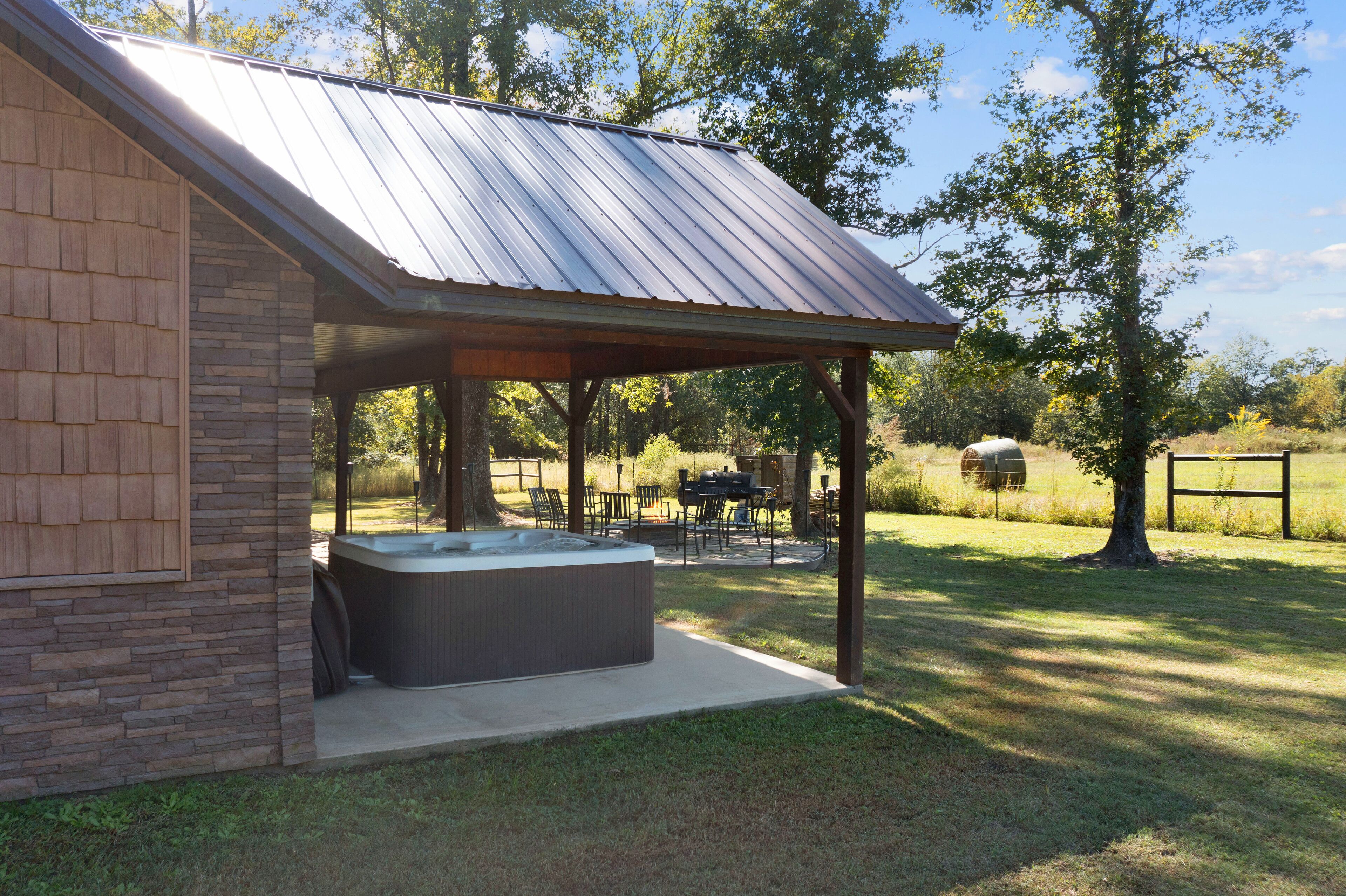 A covered outdoor area with a hot tub, stone wall, and outdoor furniture.