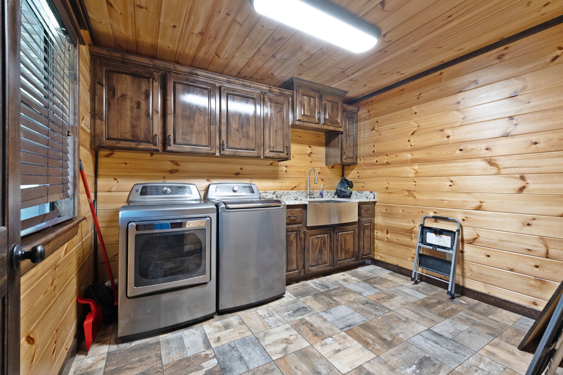 A compact kitchen with wooden walls, a built-in oven, a sink, and a small refrigerator.