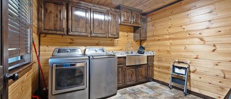 A compact kitchen with wooden walls, a built-in oven, a sink, and a small refrigerator.