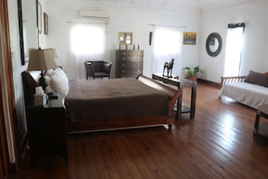 A bedroom with a wooden bed, a dresser, a chair, a desk, and a window with curtains.