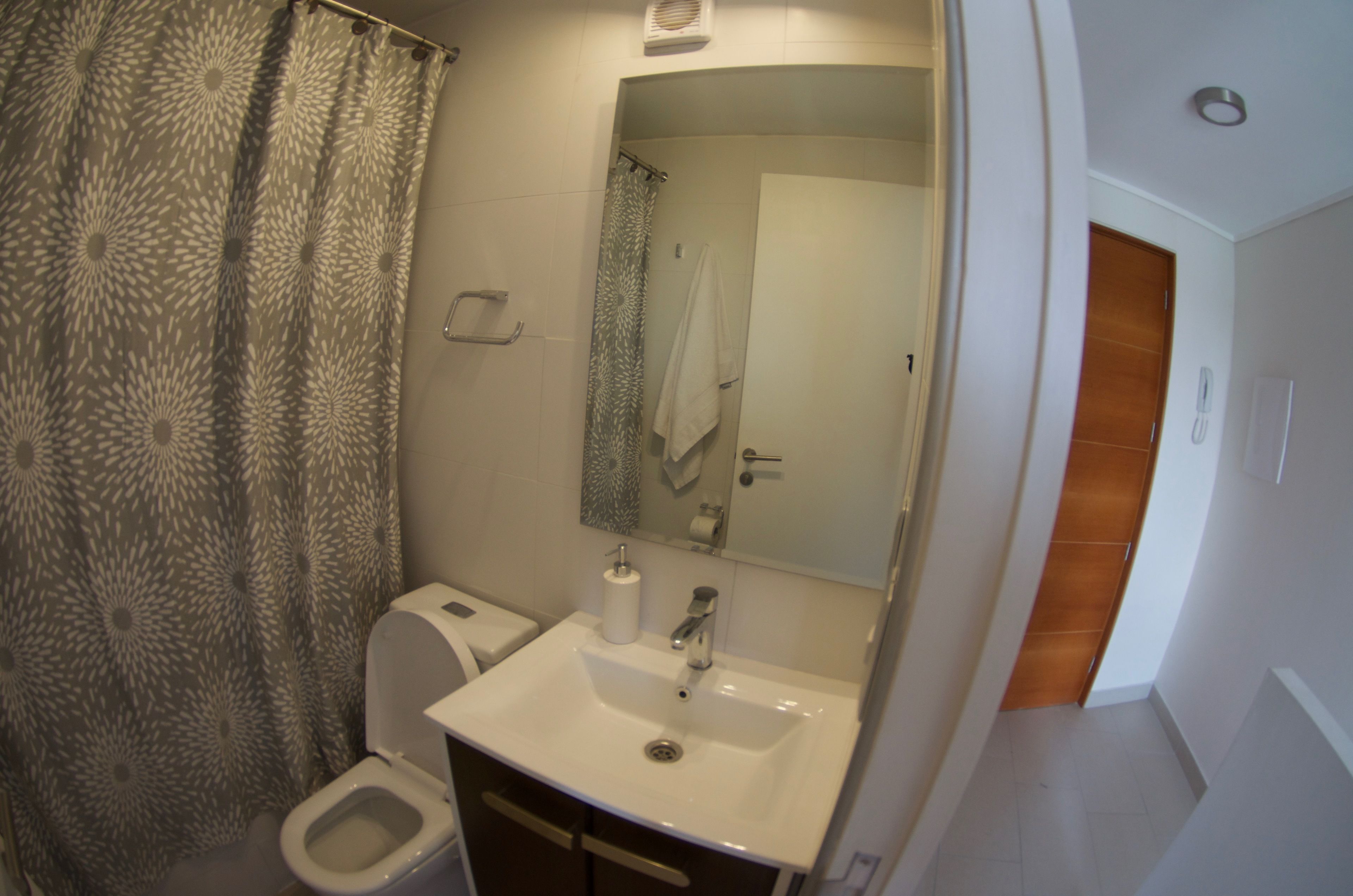 Un baño con ducha, inodoro, lavabo y espejo.