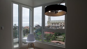 A room with large windows, a white chair, and a table with a red cup. - Lofts Plaza Yungay (Valparaiso)