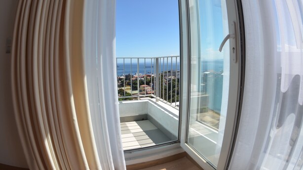 A balcony with a glass door, a view of the sea, and a cityscape in the background. - Lofts Plaza Yungay (Valparaiso)