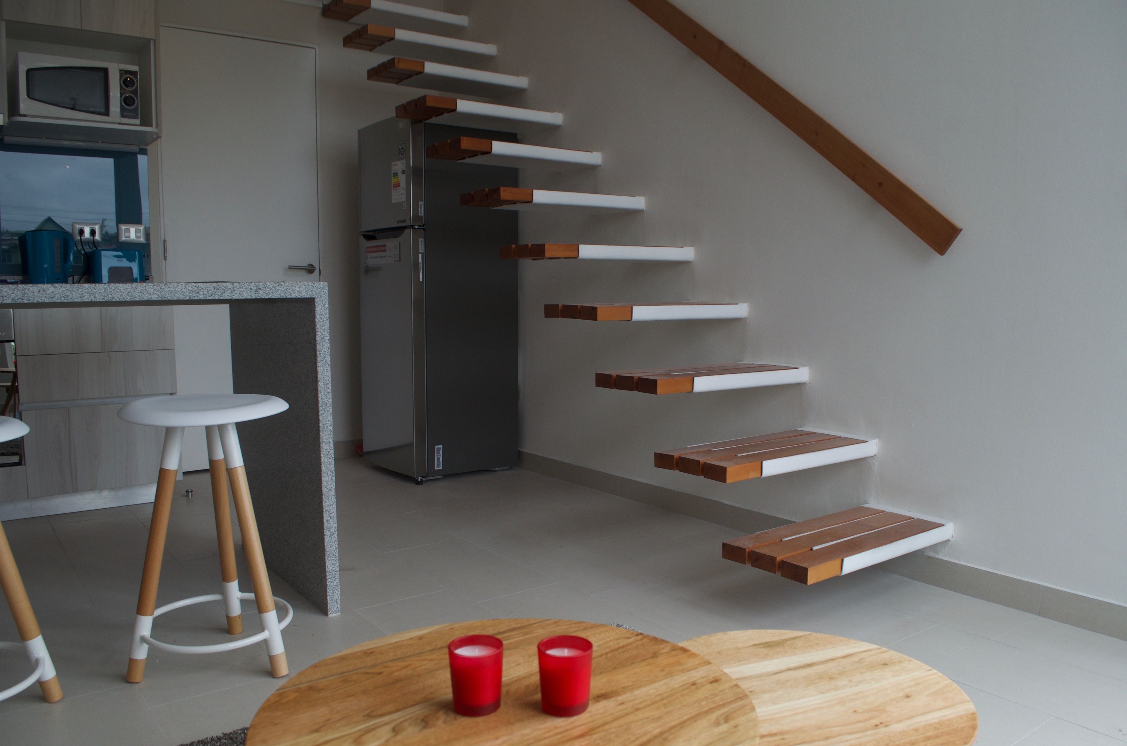 A modern kitchen with a built-in microwave, a refrigerator, and wooden stools.