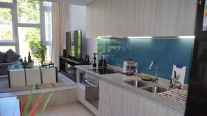 A modern kitchen with a built-in oven, a large window, and a dining area with a sofa. - Lofts Plaza Yungay (Valparaiso)