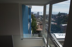 A room with a large window overlooking a cityscape with buildings and a body of water.