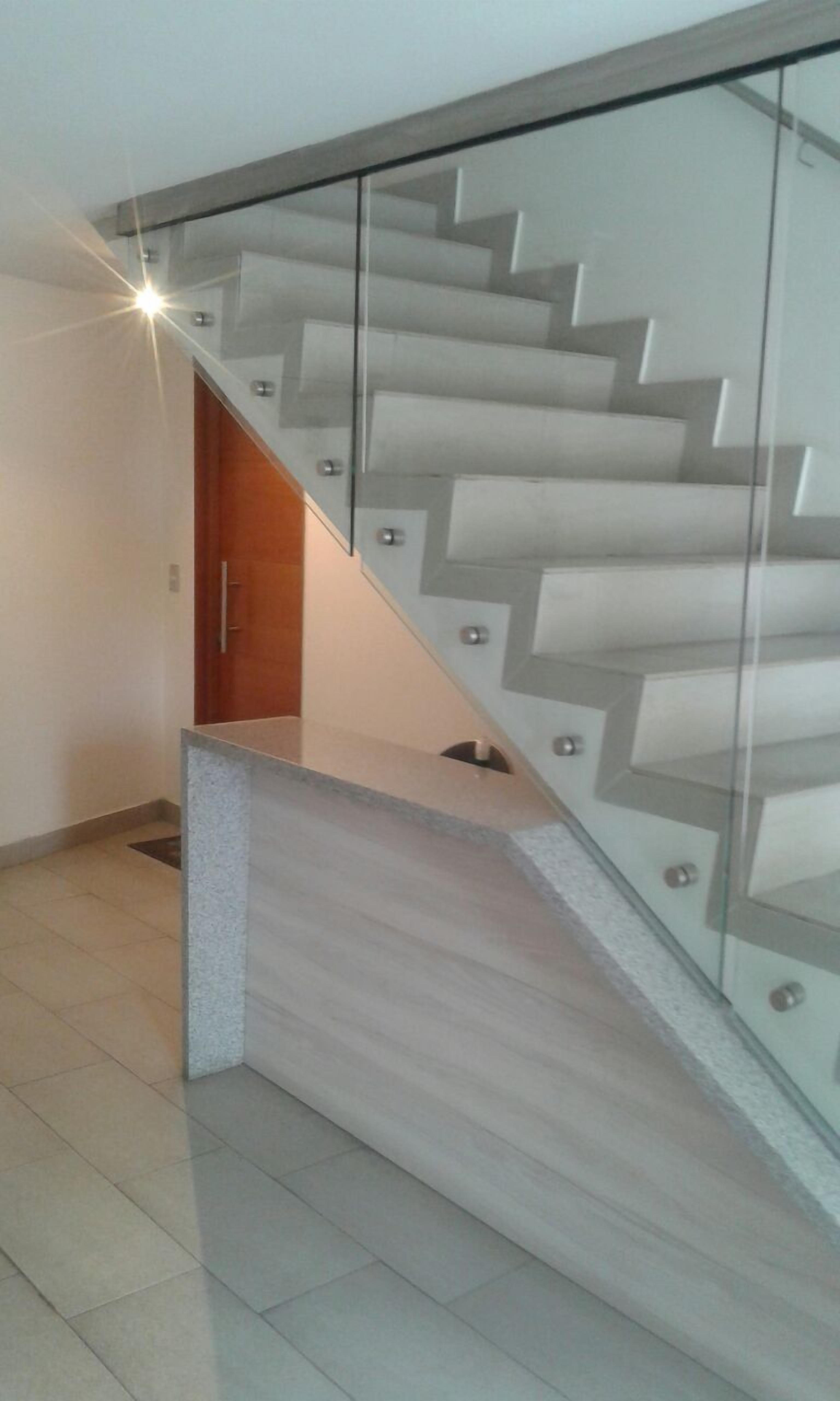 Eine moderne Treppe mit Glastrennstäben und Holzvertäfelung.