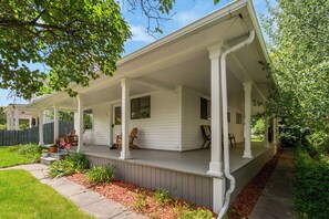 A covered porch with columns, a wooden deck, and a pathway leading to the house.