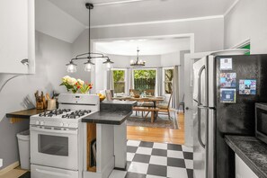 A modern kitchen with a gas stove, a refrigerator, and a dining area with a view of the outdoors.