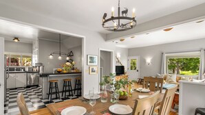 Una cocina moderna con suelo de cuadros, mesa de comedor de madera y taburetes de bar.