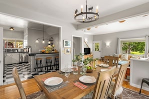 A modern kitchen with a checkered floor, wooden dining table, and bar stools.