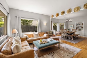 A living room with a sofa, ottoman, dining table, and chairs.