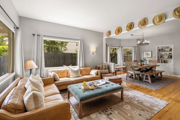 A living room with a sofa, ottoman, dining table, and chairs.