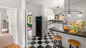 Una cocina con piso a cuadros blanco y negro, un refrigerador de acero inoxidable y una zona de bar con taburetes.