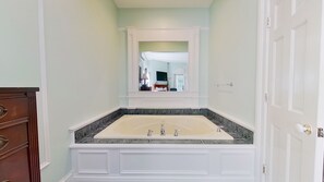 A bathroom with a double sink vanity, a mirror above the sink, and a door to the right.