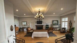 A spacious living room with a chandelier, a fireplace, and a dining area. - John Joseph Inn (Groton)