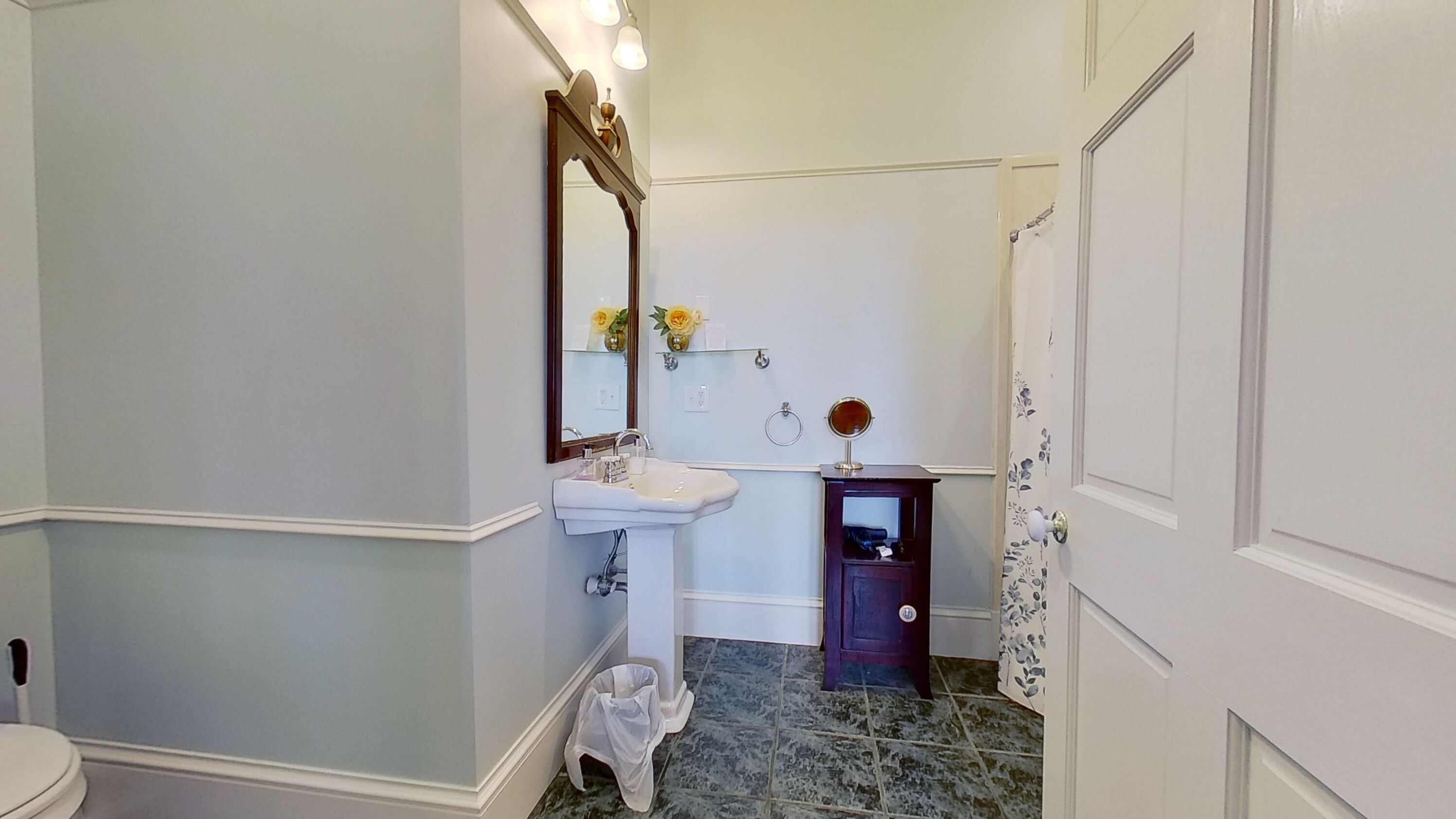 A bathroom with a white sink, a mirror, a small vanity, and a toilet.