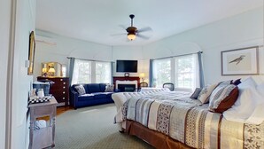 A spacious bedroom with a large bed, a sofa, a TV, and a fireplace. - John Joseph Inn (Groton)