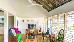 A living room with a sofa, chairs, a coffee table, and a TV. - Villa Island Breeze (Duncans)