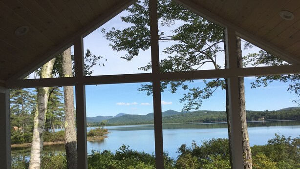 Une pièce dotée de grandes fenêtres donnant sur un lac et la forêt environnante.