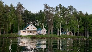 Un chalet au bord du lac, doté d’un quai, et entouré d’une forêt dense.