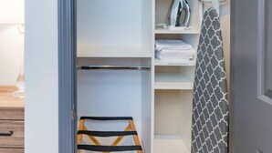 Un dressing accessible sans porte, doté d’étagères ouvertes, d’un espace pour suspendre les vêtements et d’une échelle en bois.