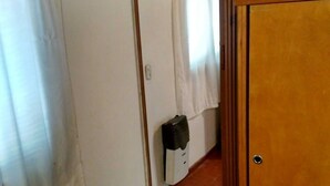 Un pasillo estrecho con paredes de madera y piso de baldosas, que conduce a una habitación con puerta de madera.