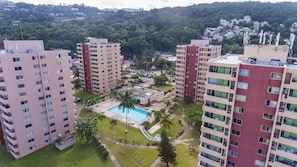 A high-rise residential building with multiple balconies, a central courtyard with a swimming pool, and surrounding greenery. - Sky Blue Beach Studio at Turtle Towers (Ocho Rios)