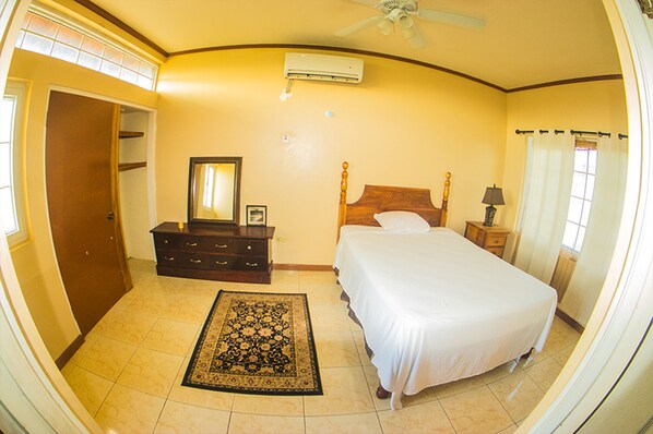 A bedroom with a bed, dresser, mirror, and a ceiling fan. - Sea Scape Villa (St. Ann's Bay)