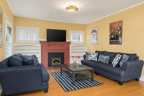 A living room with a fireplace, two sofas, a coffee table, and a TV. - Seattle Vacation Home: The Campus (Seattle)