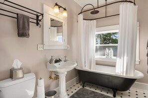 A bathroom with a black bathtub, white sink, and a window with a view of trees. - Seattle Vacation Home: The Campus (Seattle)