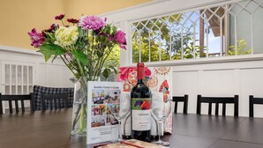 A dining table with a Seattle Visitor's Guide, a bottle of wine, two wine glasses, and a vase of flowers. - Seattle Vacation Home: The Campus (Seattle)