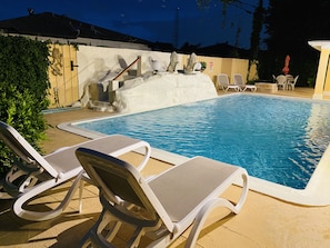A swimming pool with lounge chairs and a decorative wall.