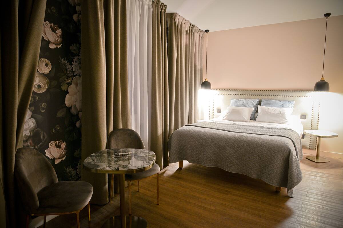 Une chambre d’hôtel avec un lit, une table ronde, deux chaises et une table de chevet.